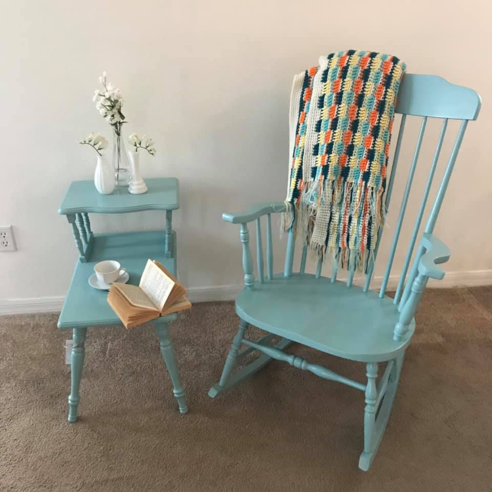 Nice blue rocking chair with a colorful blanket next to an end table