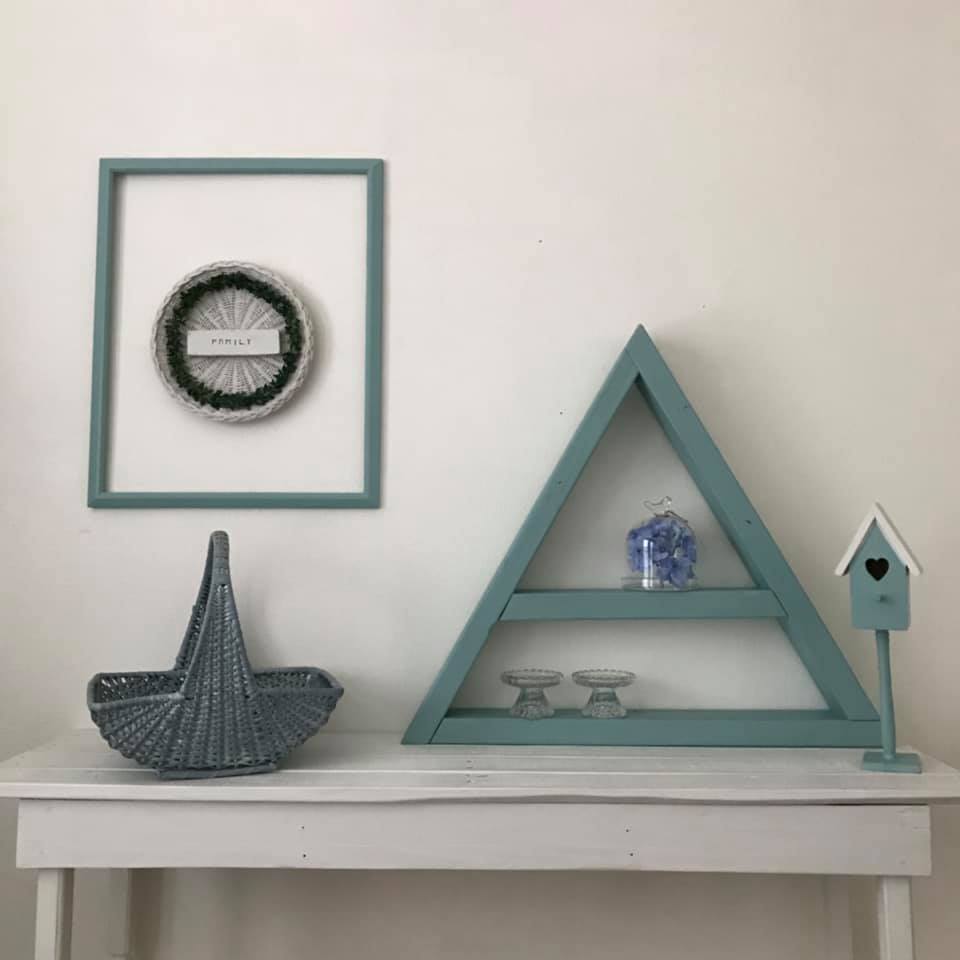 Blue triangle and basket showing on a white side table with a blue frame on the wall