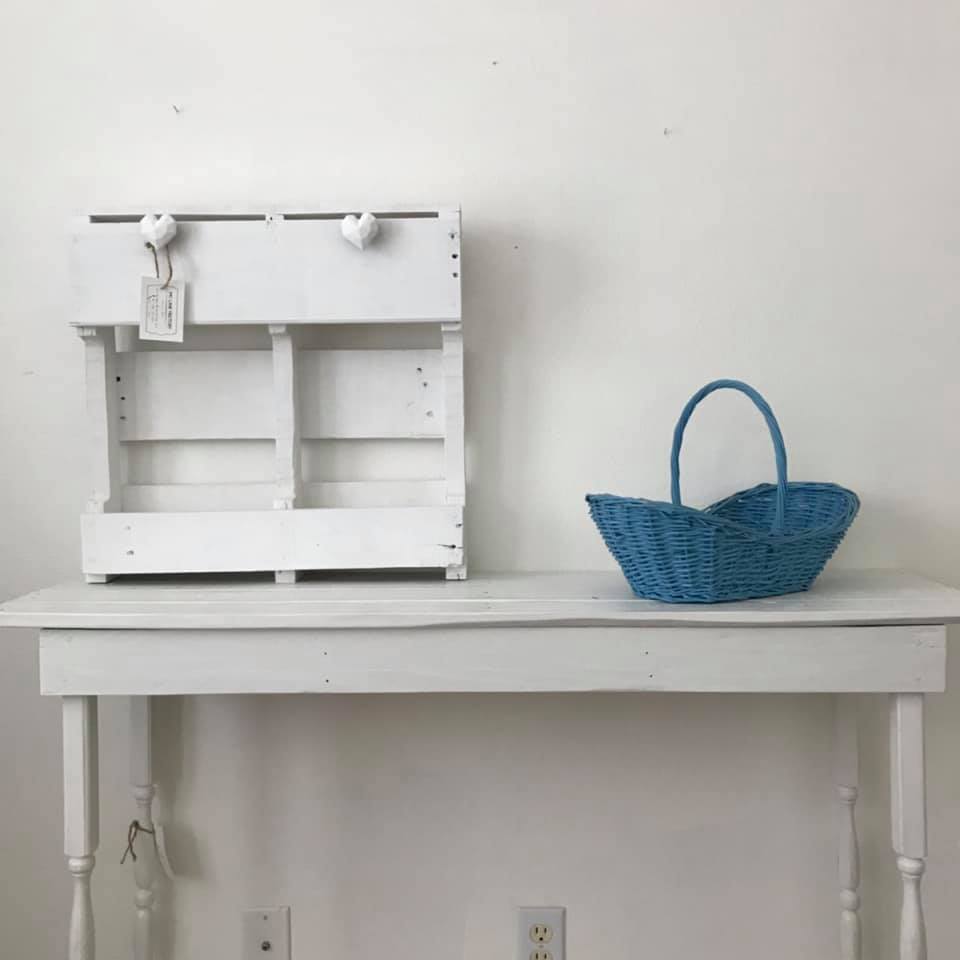 Jewelry rack and blue basket on a white side table